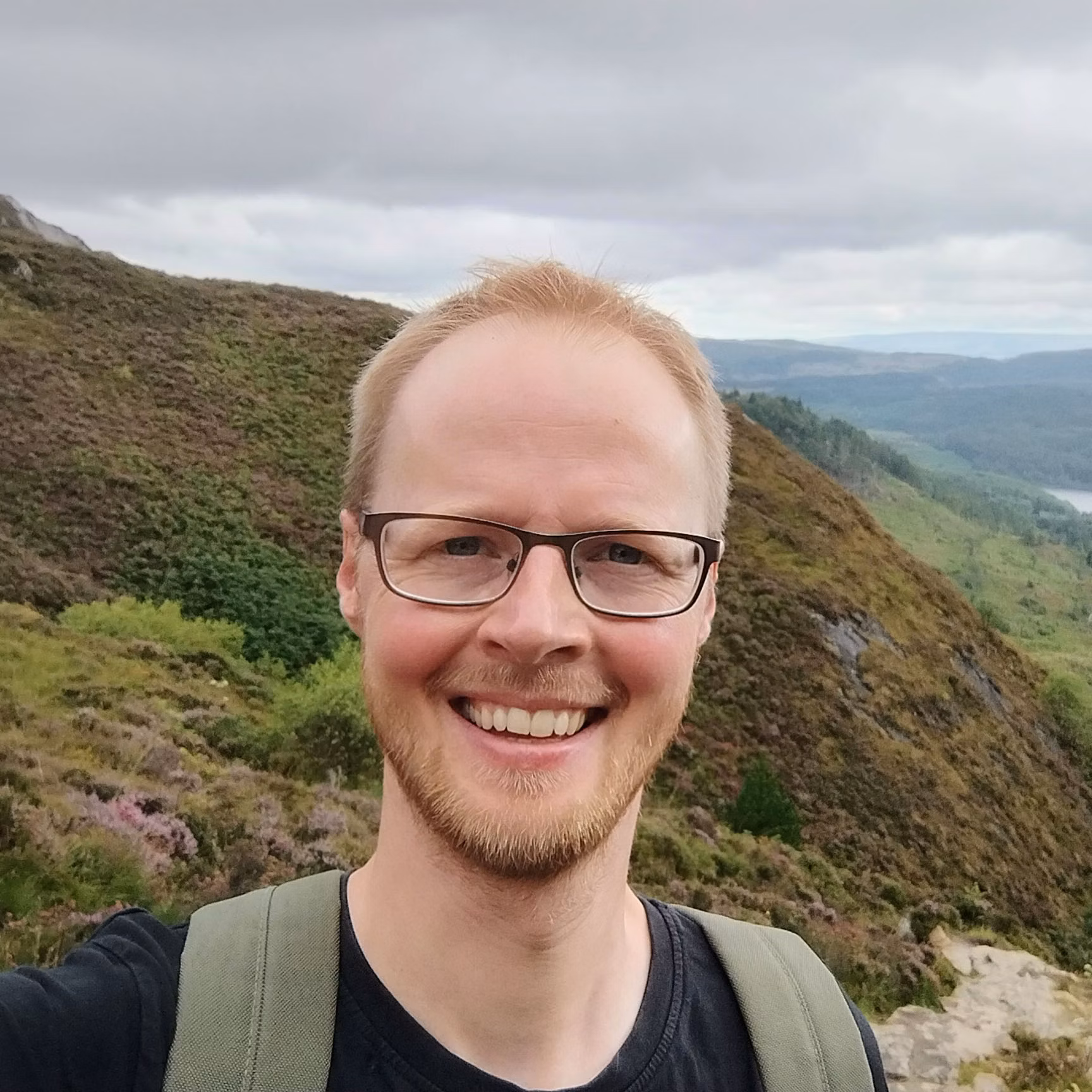 Oliver Forman looks to camera with green hills in the background